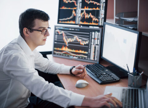Stockbroker in shirt is working in a monitoring room with display screens. Stock Exchange Trading Forex Finance Graphic Concept. Businessmen trading stocks online